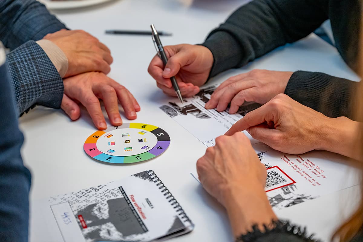 Gros plan sur des mains décryptant un poème avec une roue codée tout en écoutant un message vocal lors de l’escape game sur mesure d’EFG Bank Luxembourg, team building immersif à Luxembourg.