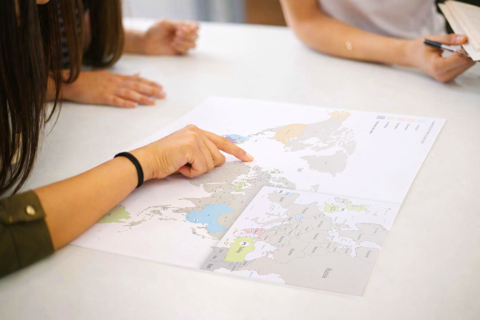 Mains de collaborateurs d’EFG Bank Luxembourg pointant et analysant une carte personnalisée lors d’un escape game sur mesure